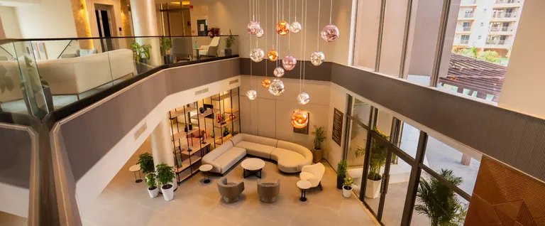 Ashiana Amarah double-height clubhouse lounge with a mezzanine, developer photo