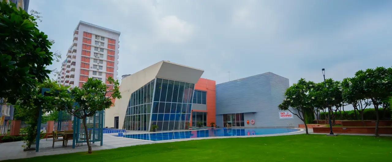 Ashiana Anmol clubhouse building with a lawn in front