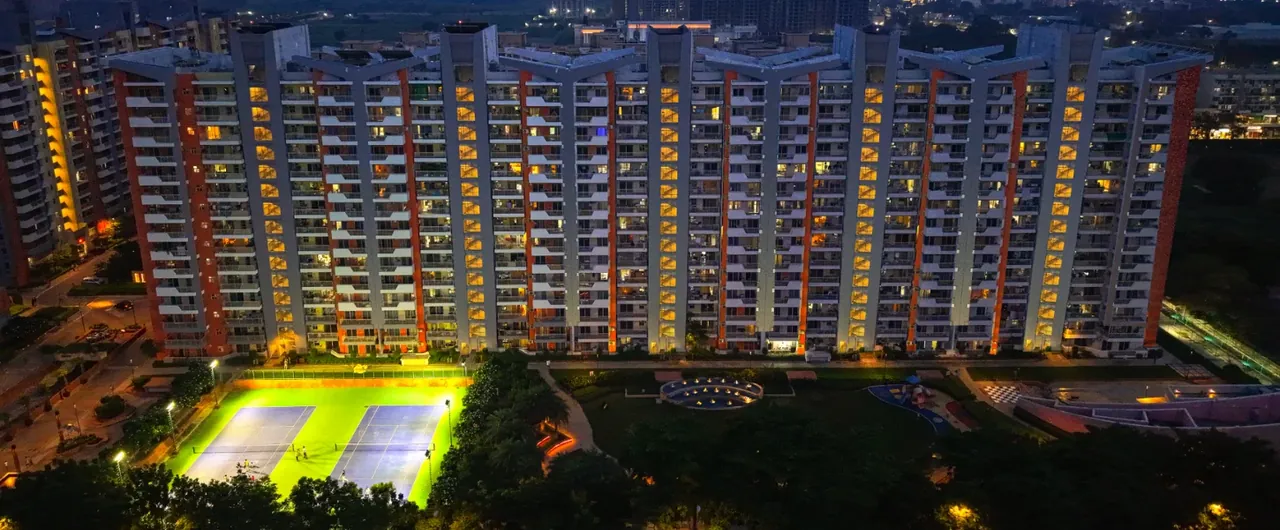 Ashiana Anmol towers and floodlit courts at night