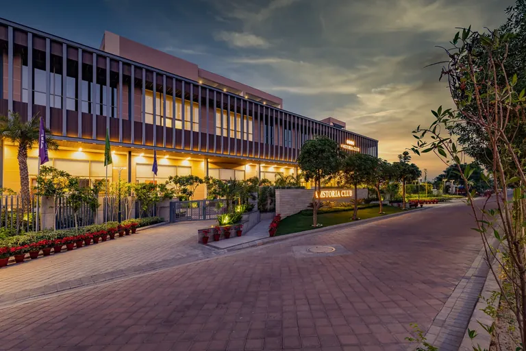 BPTP Amstoria Sanctuary Club clubhouse building lit at dusk, photo