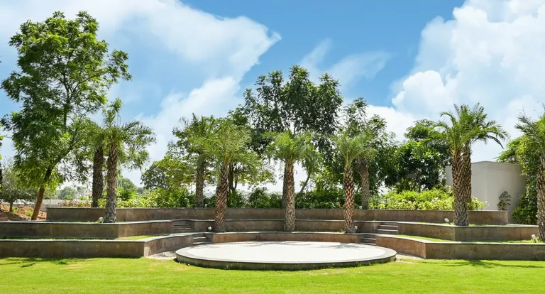 BPTP Astaire Gardens open lawn with a circular stage and palm trees