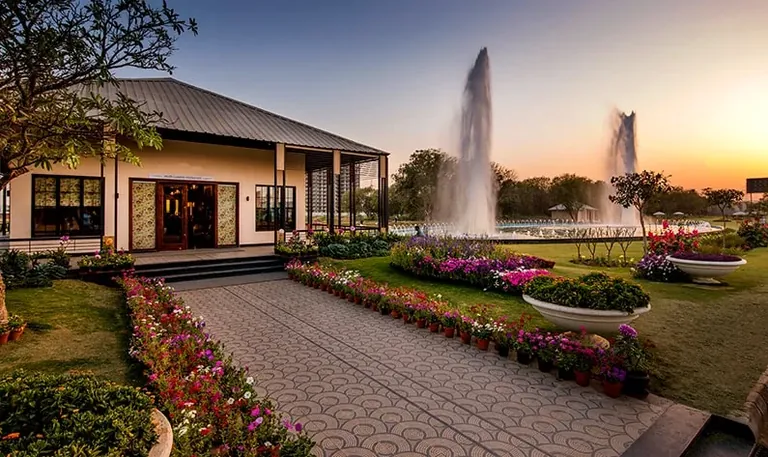 Central Park Mikasa Plots clubhouse with fountains and flower beds at sunset
