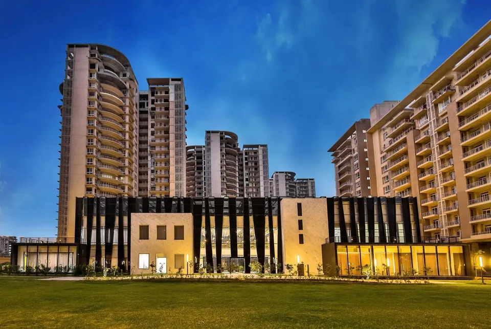 Indiabulls Enigma clubhouse lit up at blue hour with towers behind, photo
