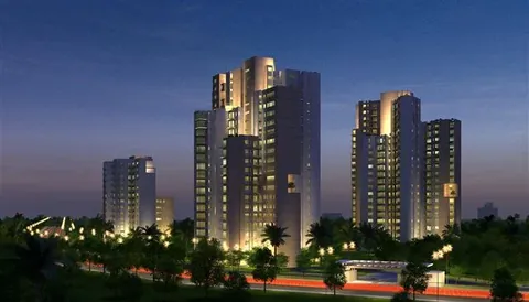 Ireo Uptown towers lit up at night behind the tree-lined boundary, artist's impression
