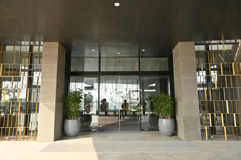 Krisumi Waterfall Residences glazed tower lobby entrance with planters, actual photo