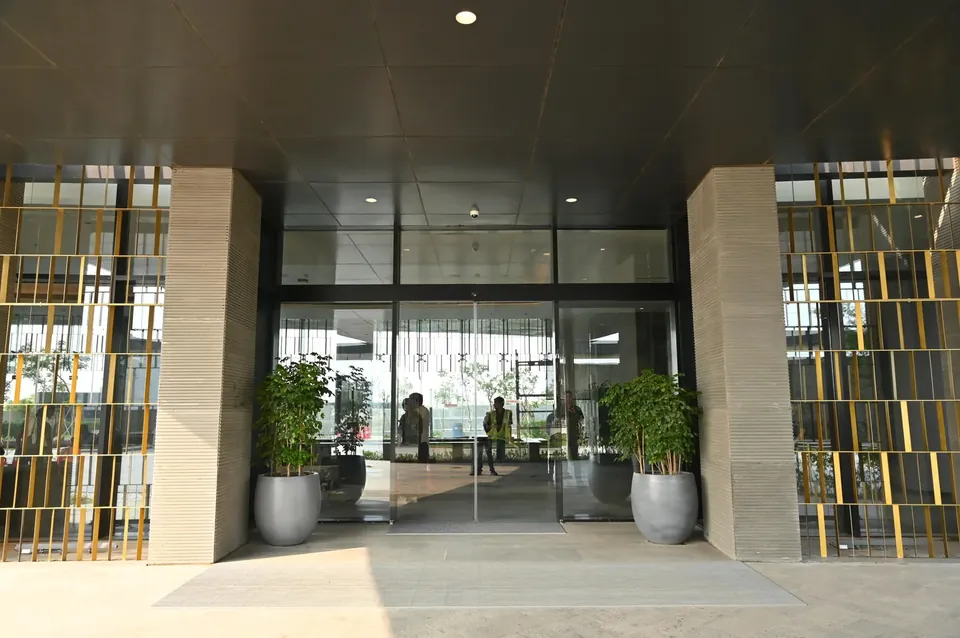 Krisumi Waterfall Residences glazed tower lobby entrance with planters, actual photo