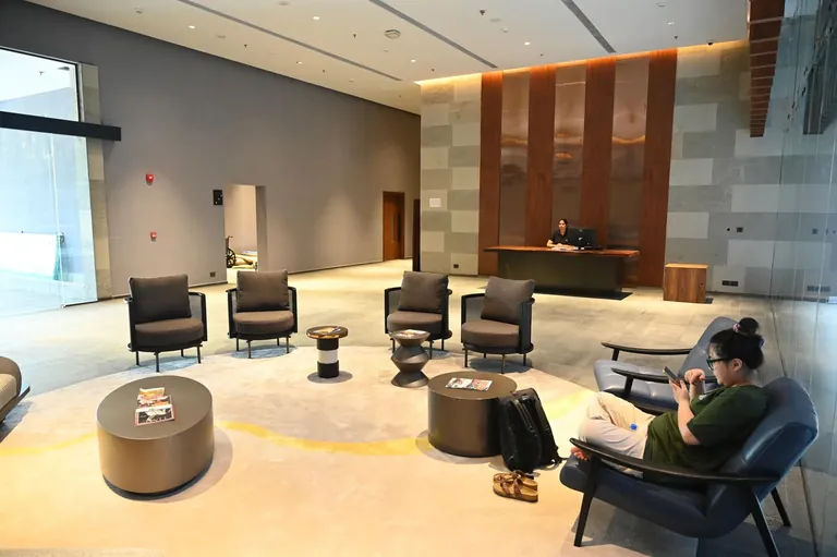 Krisumi Waterfall Residences clubhouse lounge with armchairs and timber panelling, actual photo