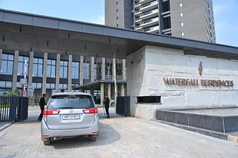 Krisumi Waterfall Residences main entrance with stone name wall and drop-off, actual photo