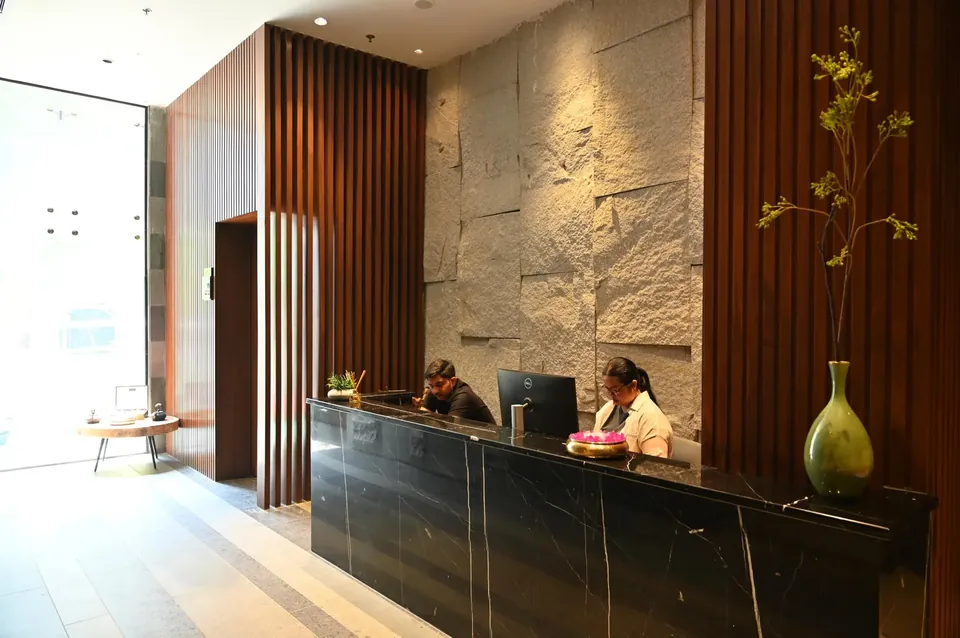 Krisumi Waterfall Residences clubhouse reception desk with stone wall, actual photo