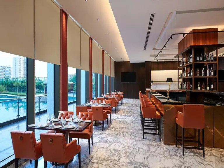 M3M Golfestate clubhouse restaurant and bar beside the pool-facing glass wall