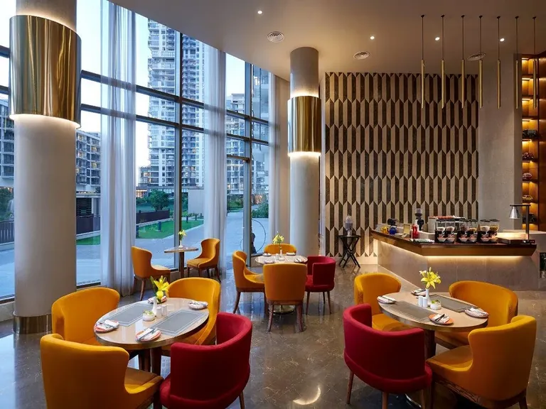 M3M Golfestate M Cafe seating area with tall windows looking out to the towers