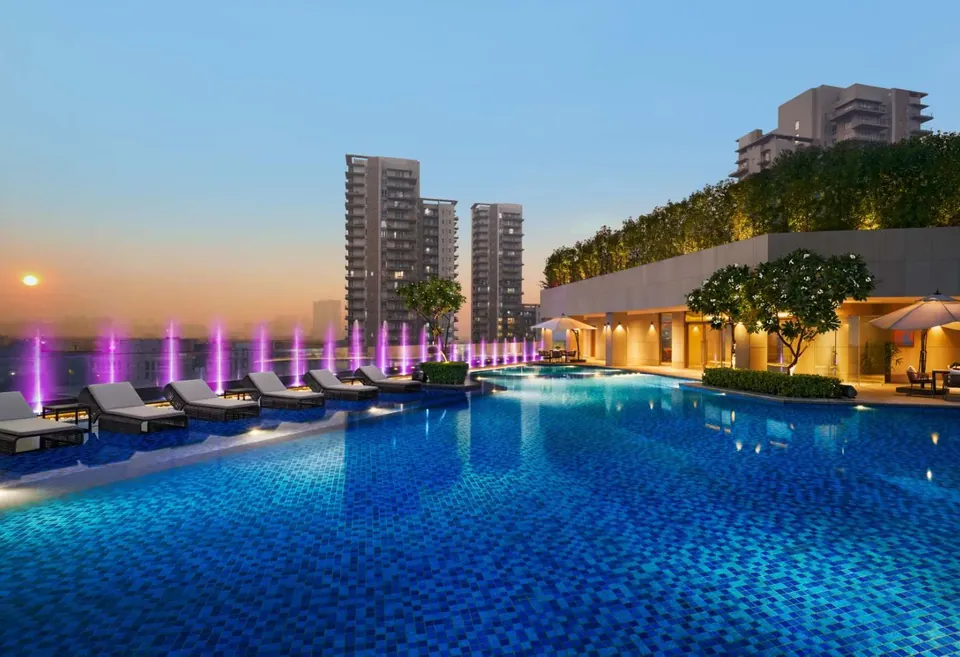 Puri Diplomatic Greens swimming pool lit at night with the towers behind