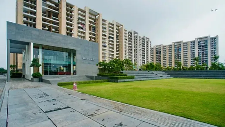 Tulip Violet glass-fronted low-rise building, paved walkway and lawn with towers in the background